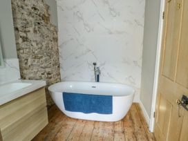A bathroom with a bathtub and washbasin at Tri Raglan Mawr Beaumaris