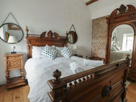 A bedroom with a bed and nightstand at Tri Raglan Mawr Beaumaris