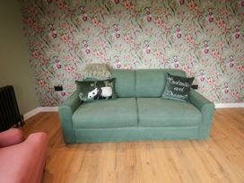 A living room with a green sofa and floral wallpaper at Unit 1 Ipswich