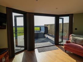 A living room with a hot tub visible outside at The Corn Silo in Ipswich