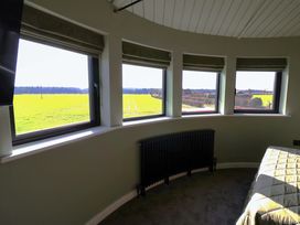 A bedroom with windows overlooking fields at The Corn Silo in Ipswich