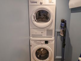 A washer and dryer stacked with a vacuum cleaner at Unit 2 in Ipswich