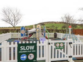 A children's play area with playground equipment and a fence at Plot 42 in Carlisle