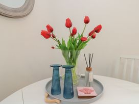 A table with tulips in a vase and decorative items at The Nest