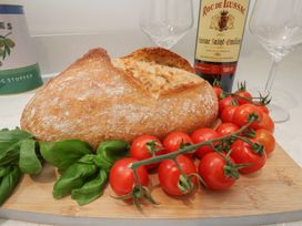 A kitchen scene with bread, tomatoes, basil, a wine bottle, and wine glasses at The Nest Buckton near Bridlington