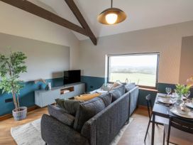 A living room with a sofa and television at Black Bird Cottage in Llangaffo
