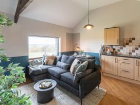 A living room with a sofa and kitchen area at Black Bird Cottage in Llangaffo