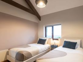 A bedroom with two beds and a window at Black Bird Cottage Llangaffo