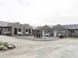 An outdoor area with stone cottages and benches at Black Bird Cottage Llangaffo