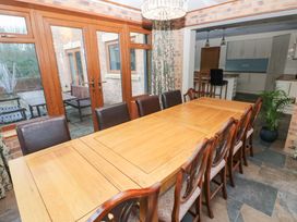 A dining room with a long table and chairs at Ty-Gan Dderwen in Llanelli