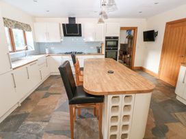 A kitchen with an island and stools at Ty-Gan Dderwen Llanelli