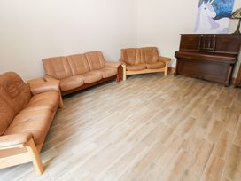 A living room with sofas and a piano at Ty-Gan Dderwen in Llanelli
