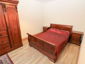 A bedroom with a bed and wardrobe at Ty-Gan Dderwen in Llanelli