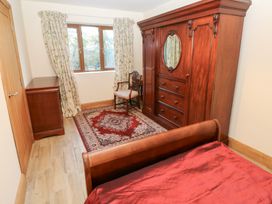 A bedroom with a wardrobe and chair at Ty-Gan Dderwen in Llanelli