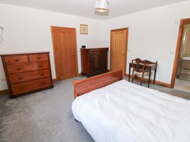 A bedroom with a bed, dressers and a chair at Ty-Gan Dderwen Llanelli