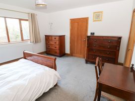 A bedroom with a bed, wardrobe, and desk at Ty-Gan Dderwen in Llanelli