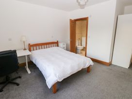 A bedroom with a bed, desk, chair, and wardrobe at Ty-Gan Dderwen Llanelli