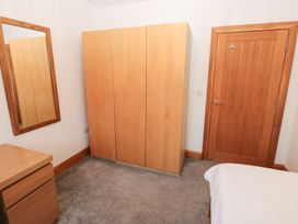 A bedroom with a wardrobe, mirror, and drawers at Ty-Gan Dderwen in Llanelli