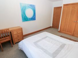 A bedroom with a bed, chair, and drawer at Ty-Gan Dderwen in Llanelli