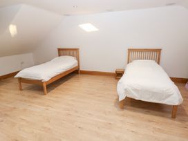 A bedroom with two single beds and a nightstand at Ty-Gan Dderwen in Llanelli