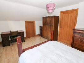 A bedroom with a bed, desk, and wardrobe at Ty-Gan Dderwen in Llanelli