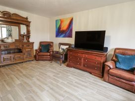 A living room with a television and seating arrangements at Ty-Gan Dderwen Llangennech