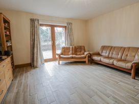 A living room with a sofa and wooden door at Ty-Gan Dderwen in Llangennech