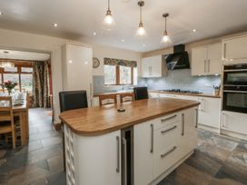 A kitchen with an island and stools at Ty-Gan Dderwen in Llangennech