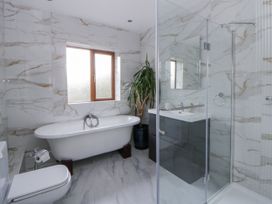 A bathroom with a bathtub, shower, and sink at Ty-Gan Dderwen in Llangennech