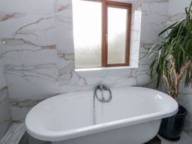A bathroom with a bathtub and a window at Ty-Gan Dderwen in Llangennech