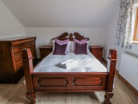 A bedroom with a wooden bed, pillows, and furniture at Ty-Gan Dderwen in Llangennech