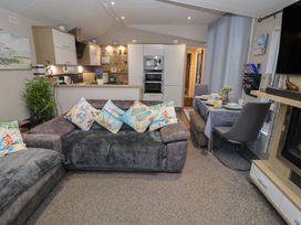 A living room with a dining area and kitchen at Offspray Court 1 in Scratby