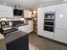 A kitchen with modern appliances and cabinets at Offspray Court 1 Scratby