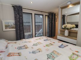 A bedroom with a bed and windows at Offspray Court 1 in Scratby