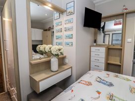 A bedroom with a bed, mirror, and television at Offspray Court 1, Scratby