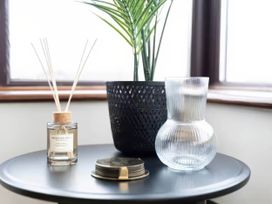 A living room with a diffuser, plant, vase and coasters at Kestrel Cottage in Llangaffo