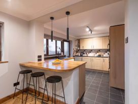 A kitchen with a bar area and appliances at Kestrel Cottage in Llangaffo