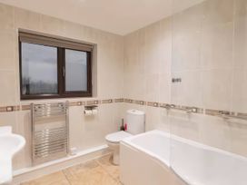 A bathroom with a bathtub, toilet, and sink at Kestrel Cottage in Llangaffo