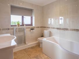 A bathroom with a bathtub, sink, and toilet at Kestrel Cottage Llangaffo