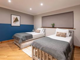 A bedroom with two single beds and a piece of wall art at Kestrel Cottage in Llangaffo