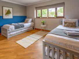 A bedroom with two beds and a window at Kestrel Cottage in Llangaffo