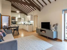 A living room with a sofa and kitchen appliances at Swan Cottage Llangaffo