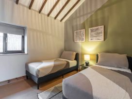 A bedroom with two beds and a window at Swan Cottage in Llangaffo