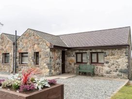 A stone house with a gravel area and bench at Wren Cottage in Llangaffo