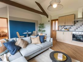 A living room with a sofa and kitchen area at Wren Cottage in Llangaffo