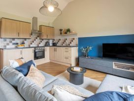 A kitchen with cabinets, stove, and a television at Wren Cottage in Llangaffo