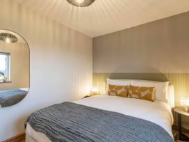 A bedroom with a bed and mirror at Blue Bird Cottage in Llangaffo