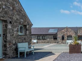 An outdoor area with stone buildings and a bench at Blue Bird Cottage in Llangaffo