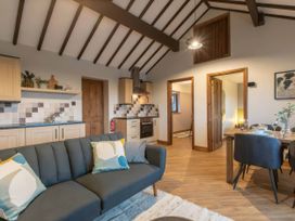 A living room with a sofa, table, and kitchen area at Blue Bird Cottage Llangaffo