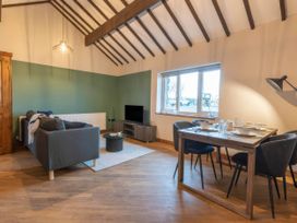 A living room with a sofa, dining table, and television at Blue Bird Cottage Llangaffo